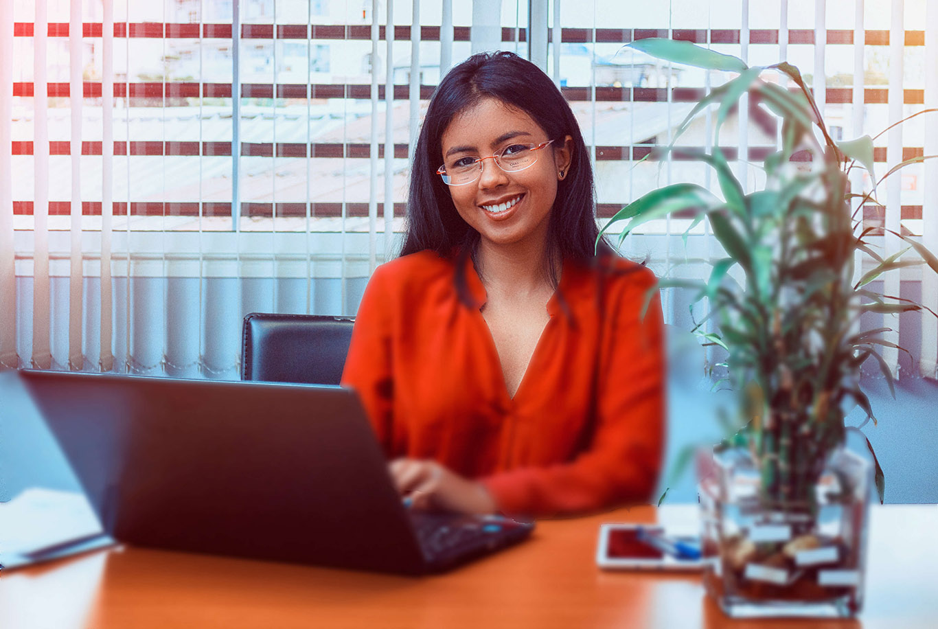 fille souriante au chemise rouge devant ordi portable